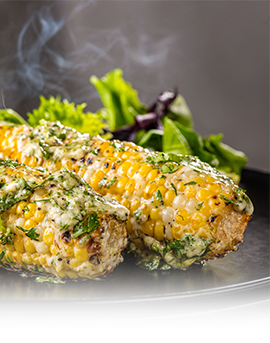 A plate of food with corn on the cob and greens.